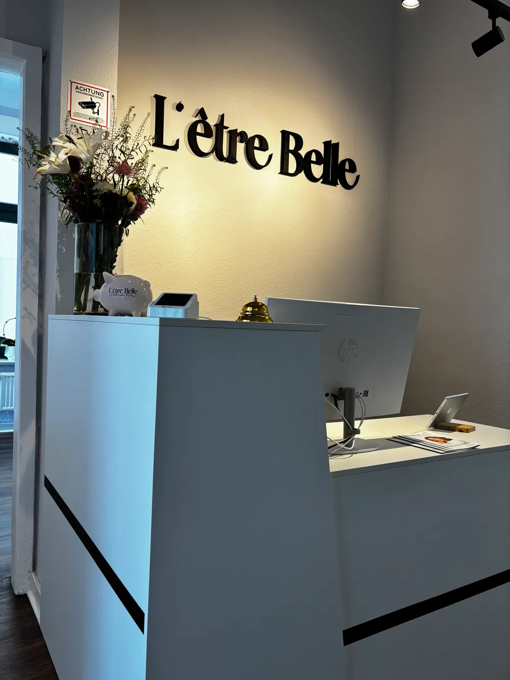 Empfangstresen von L'ÊTRE BELLE mit dem Schriftzug der Praxis in Hamburg-Harburg